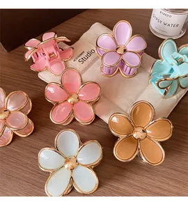 Close-up of candy color gradient flower hair clips with gold trim on wooden desk