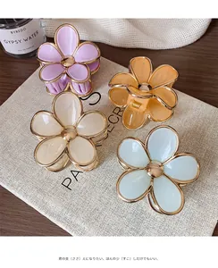 Detail of four candy-colored flower hair claws with elegant gold edges on a linen bag