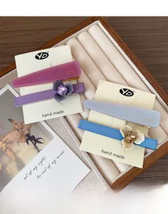 Détail de barrettes à fleurs faites à la main et pinces en acétate sur plateau