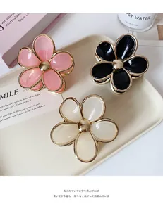 Three gradient floral hair clips with gold edges set in a stylish French lifestyle layout