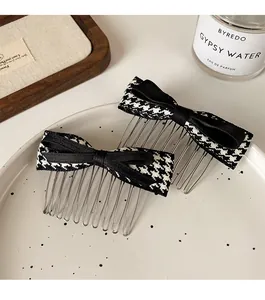 Detail of two-piece houndstooth bow hair combs on a white ceramic plate for styling