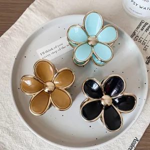 Floral hair claws in gradient candy colors with gold edges on a ceramic display tray