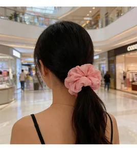 Chouchou plissé rose grand format porté en queue-de-cheval élégante par un mannequin