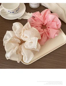 Gros plan de grands chouchous en satin beige et rose sur un plateau en céramique