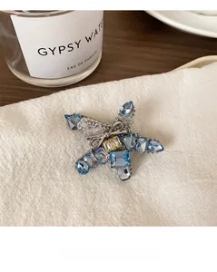 Close-up of star brooch with blue crystals and bow detail on white linen fabric