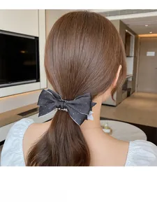 Pince à cheveux banane avec nœud en satin à pois portée sur un chignon élégant