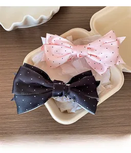 Vue détaillée de pinces à cheveux à nœuds en satin à pois roses et noirs sur un plateau