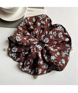Detailed view of floral chiffon scrunchie with pearls on a decorative lifestyle background