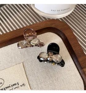 Detailed view of two small resin hair clips with sparkling rhinestone bow designs