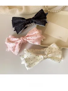 Détail de trois nœuds pour cheveux en satin à pois en noir, rose et blanc crème chic