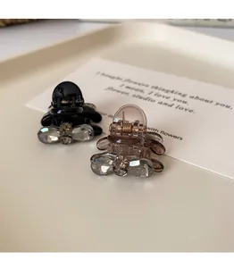 Macro detail of mini bow hair claws featuring grey crystals on black and amber bases