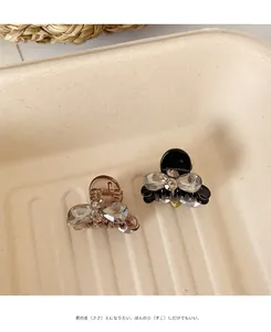 Close-up of mini bow hair clips in amber and black with sparkling rhinestone details