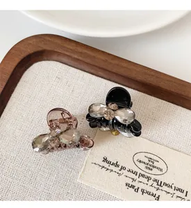 Close-up of small bow hair claws with sparkling gemstones on a rustic wooden tray