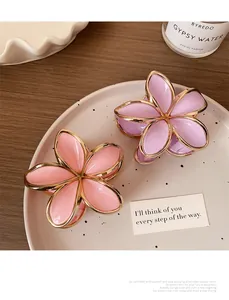 Nahaufnahme von rosa und lila Blumen-Haarklammern mit Goldrand auf einem Keramikteller