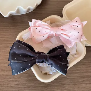 Barrettes à cheveux en satin à pois rose et noir sur fond de bois naturel