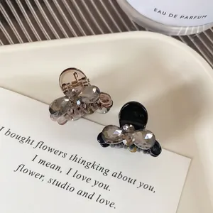 Elegant butterfly crystal mini hair clips in black and brown on a cream ceramic plate
