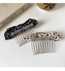Floral print bow hair side combs with metal teeth shown on a clean white desk setting