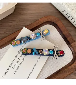 Detail of denim hair clips with colorful rhinestones and silver metal bows on wood