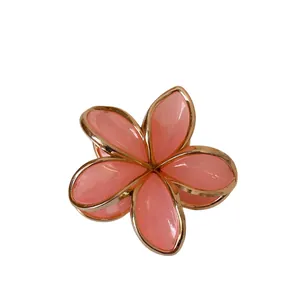 Haarklammer mit rosa-goldener Frangipani-Blüte und kontrastierenden Metallrändern