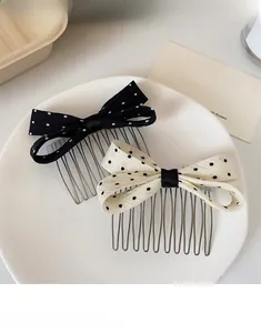 Close-up of polka dot bow hair combs set in black and cream on a white ceramic plate