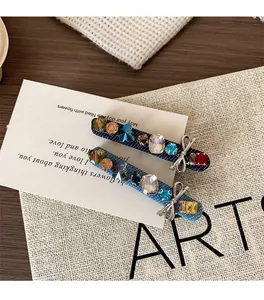 Detail of denim hair clips with colorful crystals and silver bow charms on white card