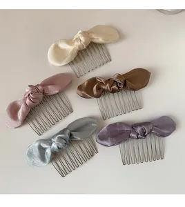 Detail of satin bow hair combs in beige pink bronze blue and purple colors