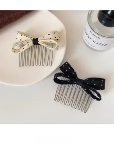 Close-up of ten-tooth metal hair combs with polka dot bow decoration in black and white