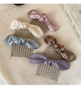 Detail of five satin bow hair combs in pink white blue brown and purple colors
