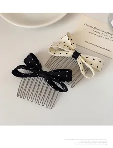 Close-up of fabric polka dot bow hair combs with metal teeth on a minimalist background