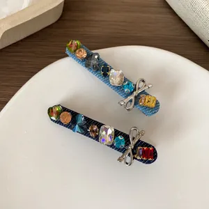 Denim hair clips set with colorful crystals and silver bow accents on a white plate