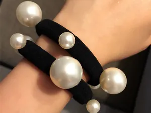 Dettaglio di due elastici per capelli neri decorati con perle bianche artificiali