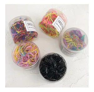 Cinq pots transparents remplis d'élastiques à cheveux colorés sur fond blanc pur