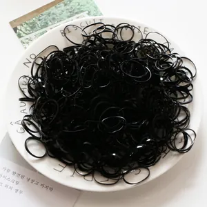 Élastiques à cheveux noirs sans couture empilés sur un plateau en céramique blanche