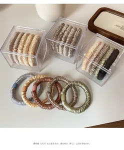 Detail of assorted satin scrunchies in earth tones displayed in an acrylic storage box