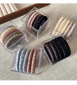 Detailed top view of silk satin scrunchies in neutral tones stored in a clear acrylic box