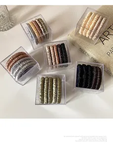 Macro view of silky satin hair scrunchies set in a clear square gift box with earthy tones