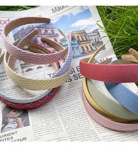 Flat lay of floral plaid and suede headbands on a newspaper over a green lawn background