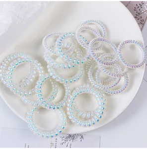Dettaglio di elastici per capelli a spirale bianco iridescente in una ciotola