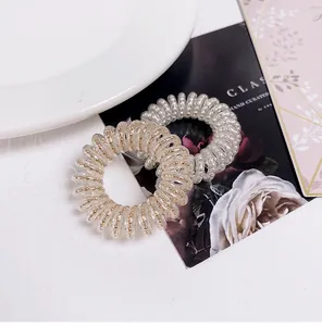 Close-up of spiral phone cord hair ties in clear and gold bead style on elegant card