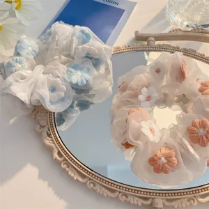 Close-up of organza hair scrunchies with pink and blue floral embroidery detail
