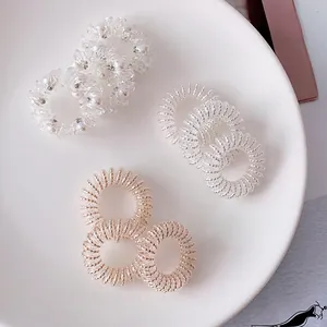 Close-up of spiral hair ties set with pearls, silver and rose gold metallic finishes