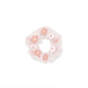 Detail of pink organza hair scrunchie with sweet floral embroidery on white background