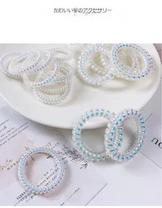 Elastici per capelli a spirale bianchi iridescenti presentati su un piatto bianco