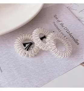 Close-up of three transparent spiral hair ties with silver beads on artistic paper
