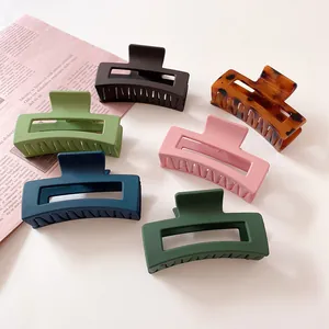 Set of six colorful matte rectangular hair claws on an aesthetic newspaper background