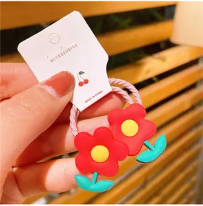 Dettaglio di un elastico per capelli a fiore per neonati con petali colorati e laccetto rosa