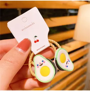 Dettaglio di elastico a spirale giallo con ciondolo avocado e confezione regalo