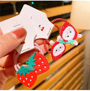 Dettaglio di elastici per capelli con fragole e coniglietti su scheda per bambine