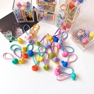 Detalle de gomas de pelo de colores con colgantes mate de dibujos en caja de regalo