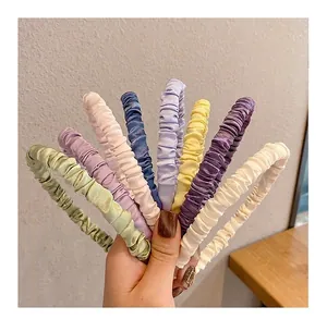 Detailed group shot of pleated satin headbands in 8 vibrant colors fanned out by hand